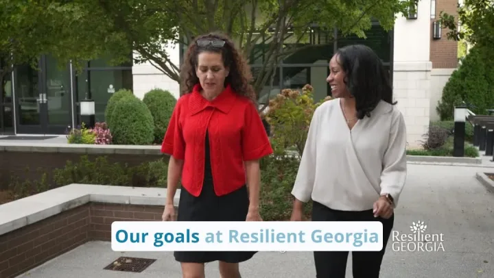 Still from a Resilient Georgia video: two staff members walk and talk outside an office.